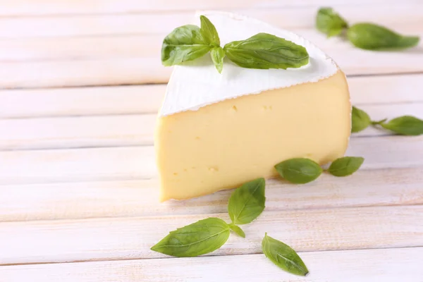 Gustoso formaggio Camembert con basilico, su tavola di legno — Foto Stock