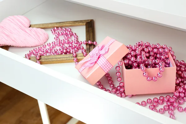 Gift box and beads in open desk drawer close up — Stock Photo, Image