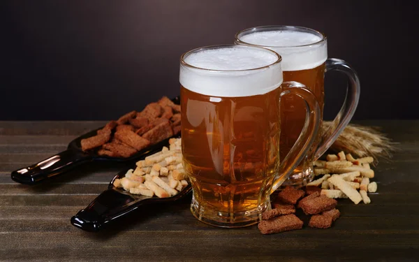 Glazen bier met snack op tafel op donkere achtergrond — Stockfoto