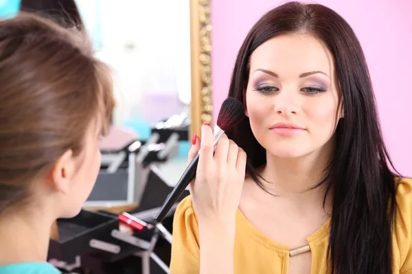 Mujer joven estilista haciendo maquillaje hermosa chica en salón de belleza —  Fotos de Stock
