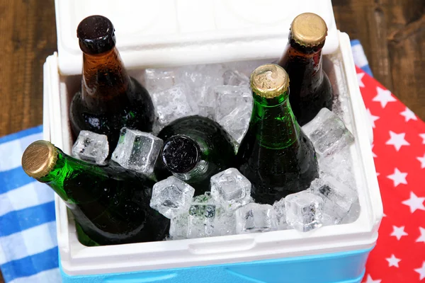 Στήθος πάγο γεμάτο ποτά σε μπουκάλια σε χαρτοπετσέτα χρώμα, σε ξύλινο φόντο — Φωτογραφία Αρχείου