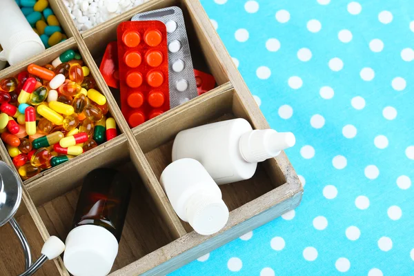 Medical pills,stethoscope,  ampules in wooden box, on color background — Stock Photo, Image