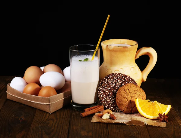 Eierlikör mit Milch und Eiern auf Tisch und schwarzem Hintergrund — Stockfoto