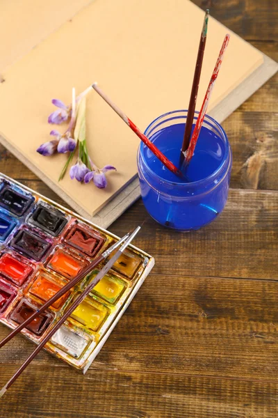 Komposition mit farbenfrohen Aquarellen, Pinseln und Skizzen auf Holzgrund — Stockfoto