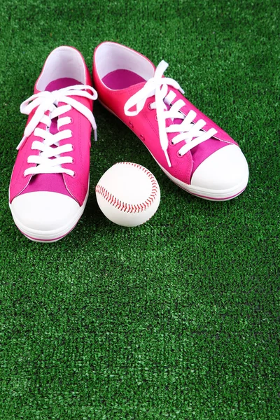 Beautiful gumshoes and baseball ball on green grass, on bright background — Stock Photo, Image