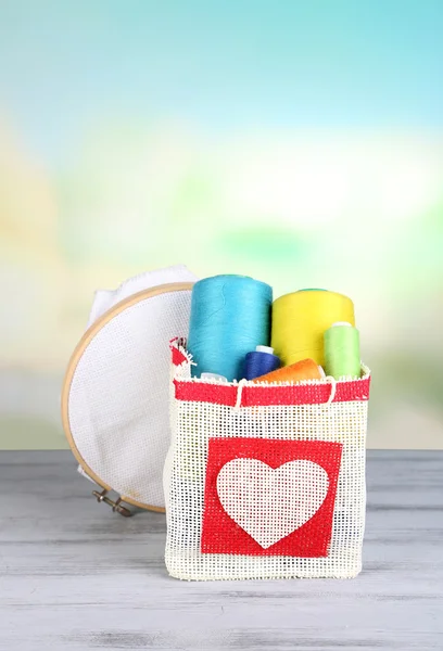 Colorful bobbins of thread  in bag, on wooden table, on light background — Stock Photo, Image