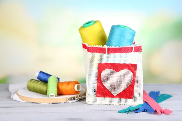 Colorful bobbins of thread  in bag, on wooden table, on light background — Stock Photo, Image