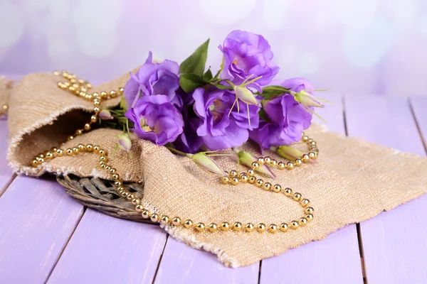 Purple artificial eustoma on sackcloth on color wooden  table, on bright background — Stock Photo, Image