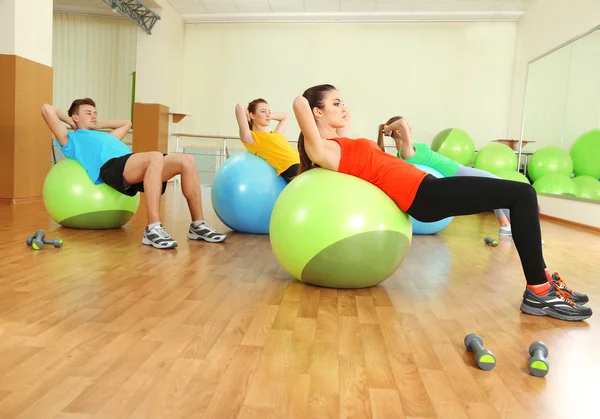 Unga vackra folk sysslar med bollar i gym — Stockfoto