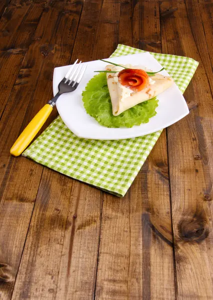 Panqueque con salmón, y mayonesa, cebolla verde, en plato, en servilleta de color, sobre fondo de madera — Foto de Stock