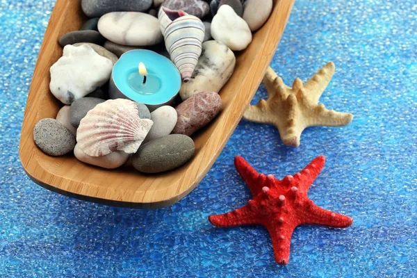 Houten kom met spa stenen, zeeschelpen en kaarsen op kleur achtergrond — Stockfoto