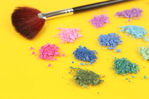Regenboog verpletterd oogschaduw en professionele make-up borstel op gele achtergrond — Stockfoto