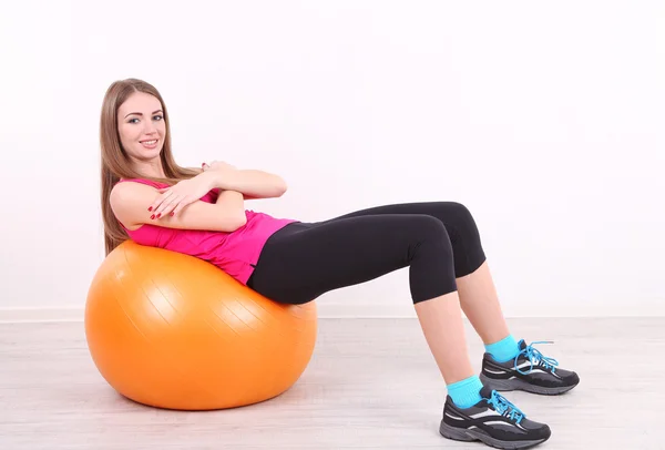 Young beautiful fitness girl exercising with orange ball in gym — Stock Photo, Image