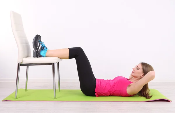 Young beautiful fitness girl exercising on green mat, in gym — Stock Photo, Image