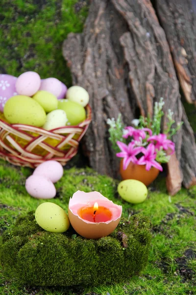 Konzeptionelle Osterkomposition. brennende Kerze im Ei, Ostereier und Blumen auf grünem Grashintergrund, Nahaufnahme — Stockfoto