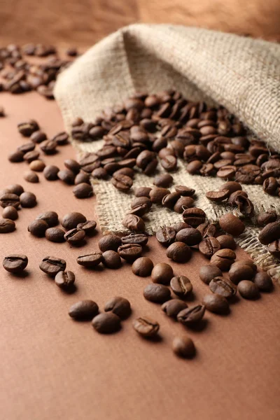 Kávová zrna na stole na hnědé pozadí — Stock fotografie