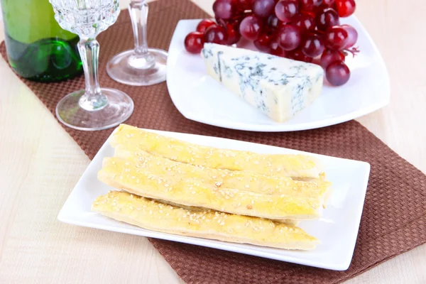 Cheese, grape and bread sticks on plate on wooden table background — Stock Photo, Image