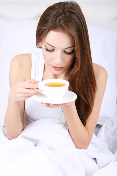 Joven hermosa mujer con taza de té en la cama de cerca — Foto de Stock