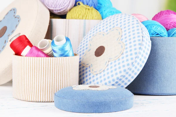 Decorative boxes with colorful skeins of thread on table on bright background — Stock Photo, Image