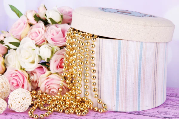 Декоративная коробка с бусами и цветами на столе на ярком фоне — стоковое фото