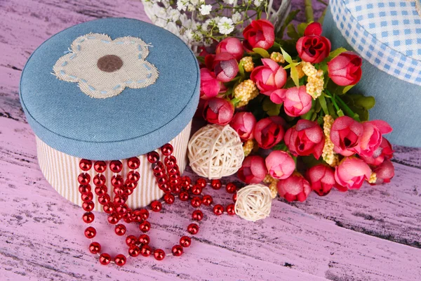 Dekorativa lådor med pärlor och blommor på trä bakgrund — Stockfoto