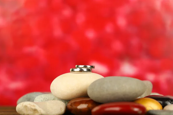 Anneaux de mariage sur des rochers sur fond rouge — Photo