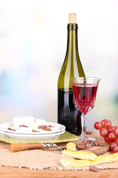 Talerz z serem, winogrono i kieliszek do wina na stole, na jasnym tle — Zdjęcie stockowe