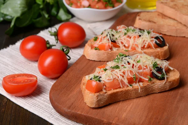 Lahodná bruschetta s rajčaty na řezací desce zblízka — Stock fotografie