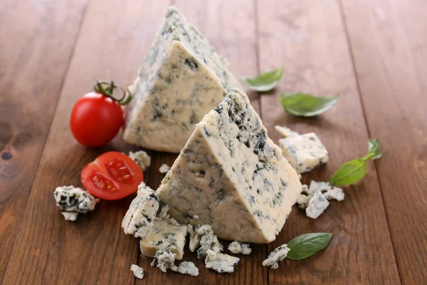 Вкусный голубой сыр с базиликом и помидорами, на деревянном столе — стоковое фото