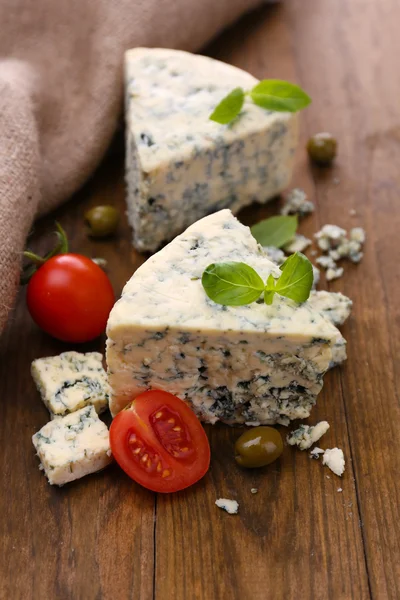 Смачний блакитний сир з помідорами, оливками та базиліком, на дерев'яному столі — стокове фото