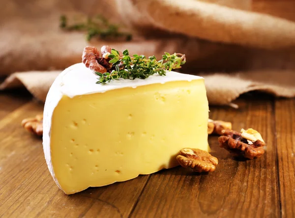 Chutný sýr camembert s tymiánem a ořechy, na dřevěný stůl — Stock fotografie