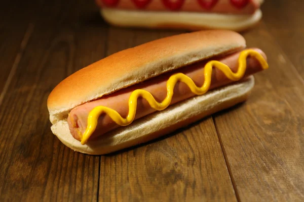 Sabrosos perritos calientes en mesa de madera — Foto de Stock