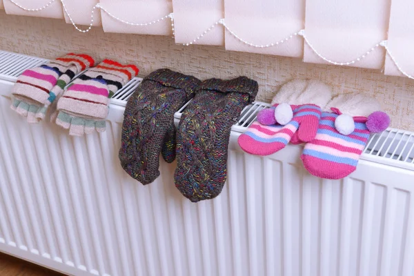 Knitted gloves drying on heating radiator — Stock Photo, Image