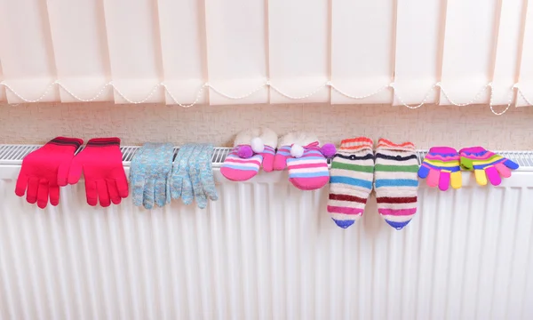 Knitted gloves drying on heating radiator — Stock Photo, Image