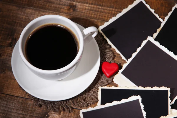 Composizione con tazza di caffè, cuori decorativi e vecchie foto in bianco, su sfondo di legno — Foto Stock
