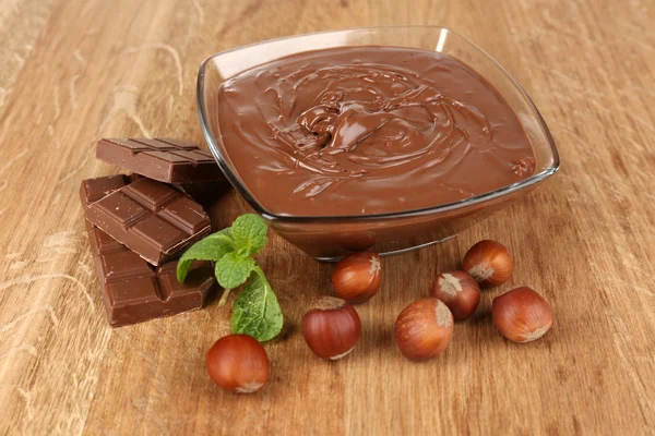 Sweet chocolate hazelnut spread with whole nuts and mint on wood background — Stok Foto