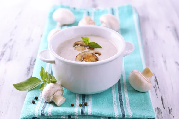 Mushroom soup in white pot, on napkin,  on wooden background — Stock Photo, Image