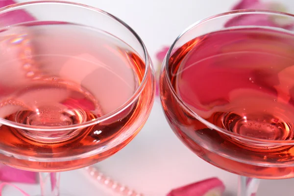 Composición con vino espumoso rosa en copas y pétalos de rosa aislados en blanco — Foto de Stock