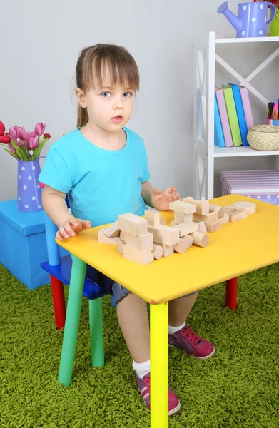 Küçük kız odasındaki masada oturan inşaat blokları ile oynuyor. — Stok fotoğraf