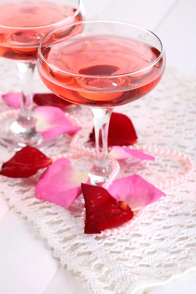 Sammansättning med rosa gnistra vin i glasen och rosenblad isolerad på vit — Stockfoto