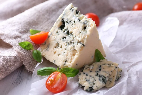 Tasty blue cheese with tomatoes and basil on paper — Stock Photo, Image