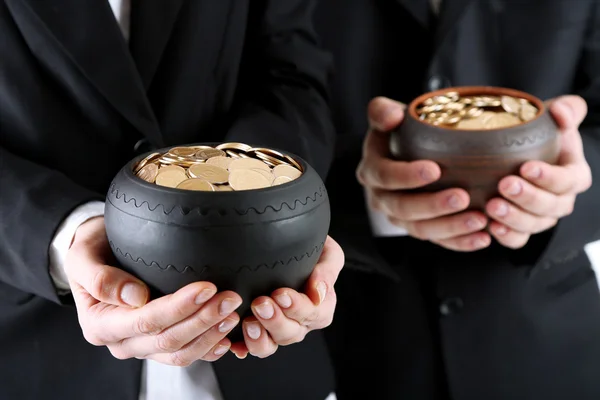 Twee keramische potten met gouden munten in mannelijke en vrouwelijke handen, geïsoleerd op witte achtergrond — Stockfoto