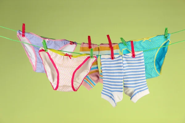 Vestiti per bambini appesi sulla clothesline, sullo sfondo di colore — Foto Stock