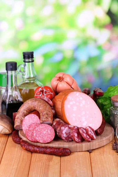 Different sausages on wooden table on natural background — Stock Photo, Image