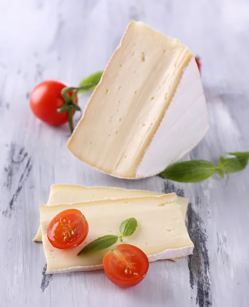 Schmackhafter Camembert-Käse mit Tomate und Basilikum, auf Holztisch — Stockfoto