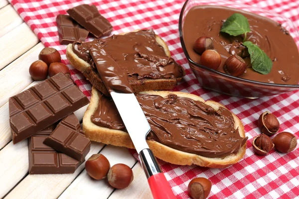 Bröd med söt choklad hasselnöt sprida på trä bakgrund — Stockfoto