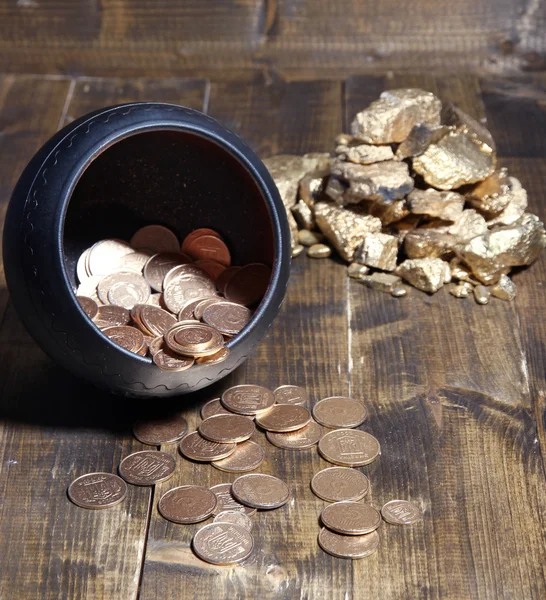 Golden coins falling out from pot, on wooden background — Stock Photo, Image