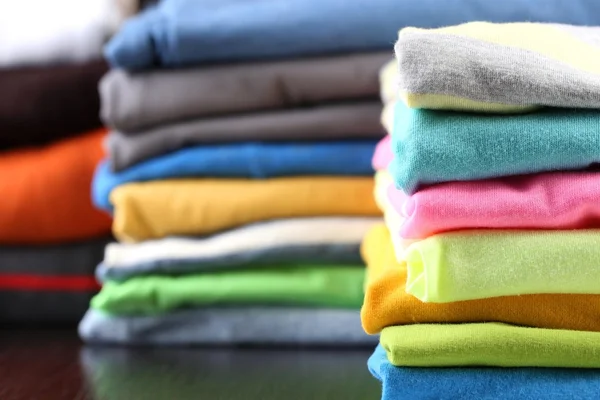 Stack of colorful clothes, on dark background — Stock Photo, Image