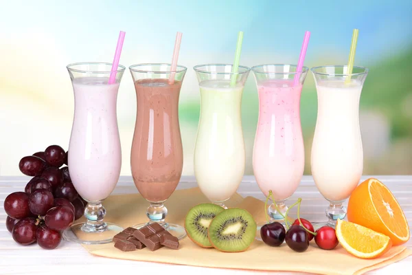 Milk shakes avec des fruits sur la table sur fond bleu clair — Photo