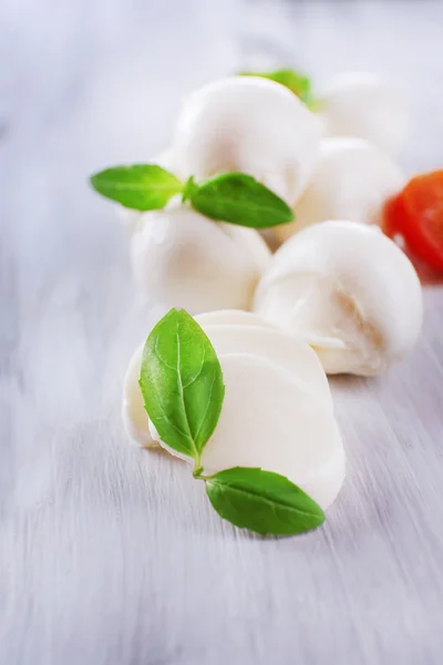 Tasty mozzarella cheese with basil and tomatoes, on wooden table — Stock Photo, Image